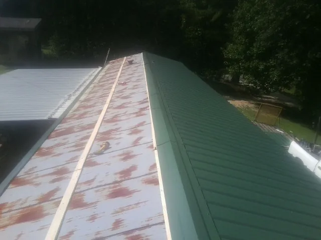 Old rusted panels beside newly installed green metal roofing — Wind Damage Roof Repair by Roofing Brothers in Sulphur
