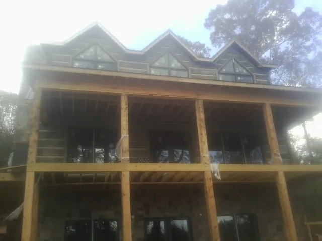 Dormers and porch framing on a large log home under construction — Roof Coating work by our crew in Sulphur