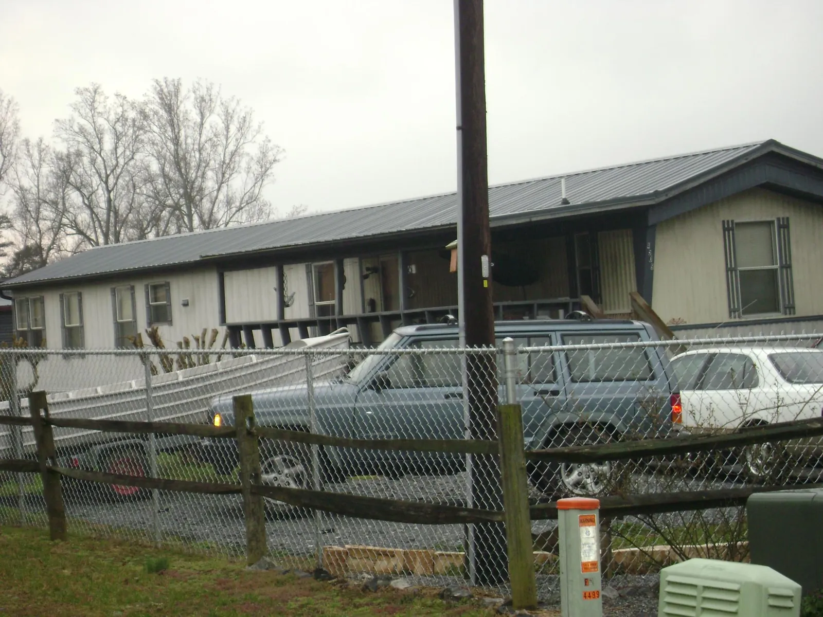 Dark metal roof on a long single story building behind a chain link fence in Sulphur