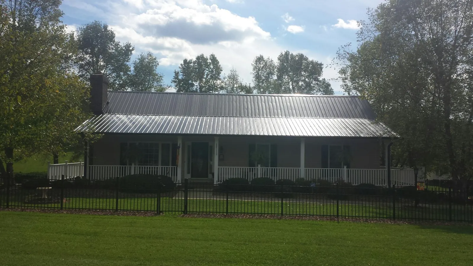 Gray metal roof on a brick ranch with a full width front porch — Gutter Guard Installation work by our crew in Sulphur