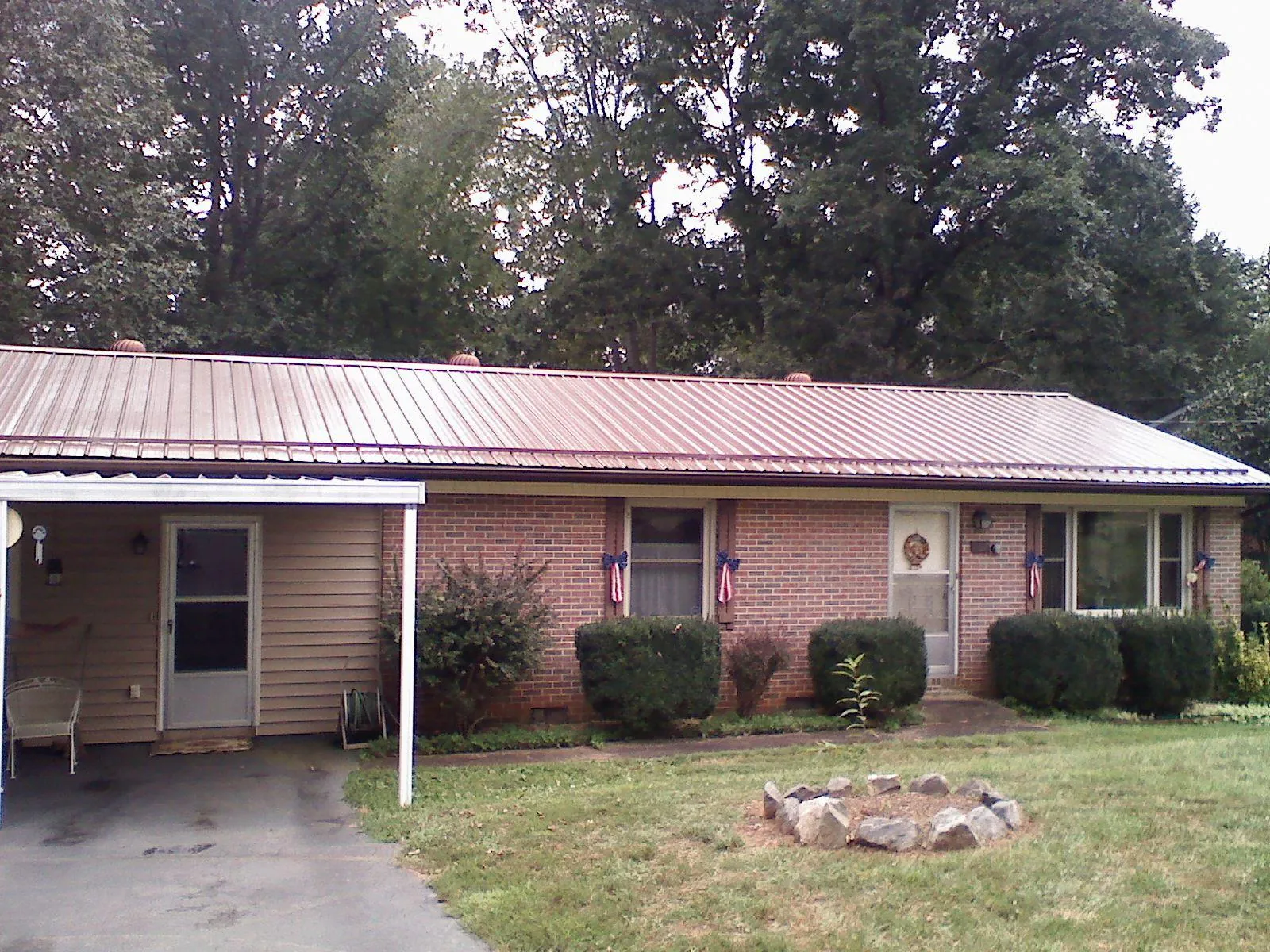 Bronze metal roof and carport on a brick ranch home — Roof Repair work by our crew in Sulphur