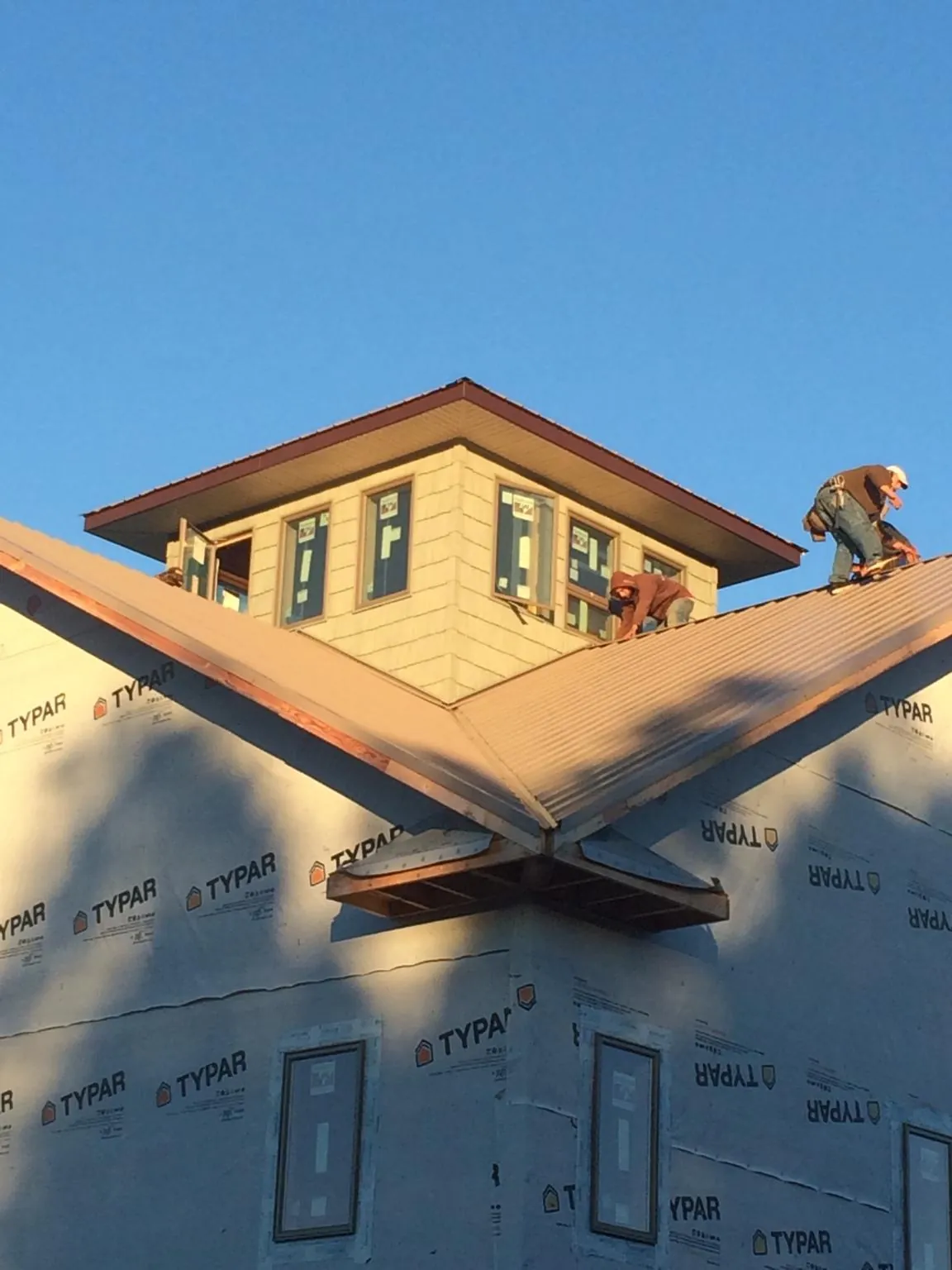 Roofers working around a rooftop cupola on a new metal roof at sunset — Roof Waterproofing in Sulphur by Roofing Brothers